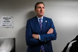 a man in a suit stands with his arms crossed