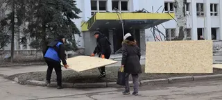 公民在乌克兰斯洛维亚斯克的一个受损建筑前携带大片合板,作为重建工作的一部分.