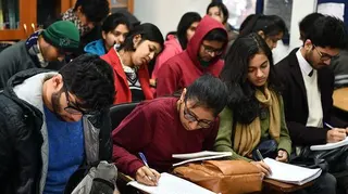 Students wearing woolens - jackets, scarves and sweaters - take notes in a class at the Ramjas College of Delhi University