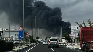 Cars on a road in Qatar, as smoke billows into the sky after an alleged Iranian attack