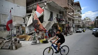 A youth rides his bike near a damaged house decorated with Shia Muslim Ashura flags as the Shia community marks the holy month of Ashura which commemorates the day one of Prophet Mohammed's grandsons was killed during a battle with unjustice King Yazid in 680 AD in Karbala of Iraq, in the southern Lebanese coastal city of Tyre on June 23, 2026.