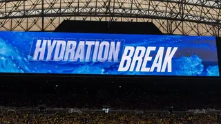 Television screen inside a stadium shows the words "hydration break" at the World Cup