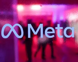 People walk behind a logo of Meta Platforms during a conference in Mumbai, India, in 2023