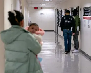 person holds baby while standing in hallway with two other people down the hallway