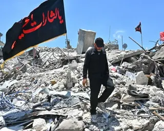 man walks across rubble left by collapsed buildings.