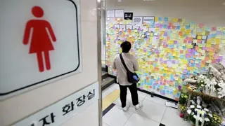 韓國一處女性廁所的牆面貼滿繽紛的便利貼，一名民眾正在閱讀上面的訊息，現場還擺放著鮮花。