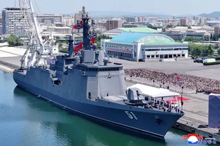 The North Korean destroyer Choe Hyon, a large grey warship, at a commissioning ceremony at a port.