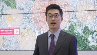中央電子監控中心主任林合格站在一幅標示有圓形區域的大型空拍地圖前。