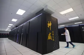 A person in a white lab coat walks past the a supercomputer with gold Chinese characters