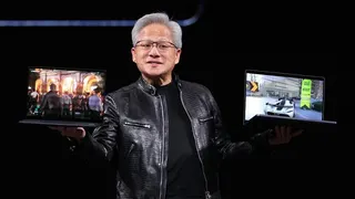 Nvidia's chief executive Jensen Huang holds up two laptop computers on a stage while wearing his trademark black leather jacket.