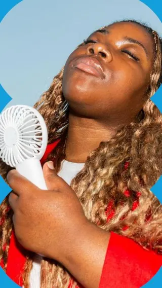 Woman holds up a fan to her face