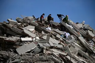 People search for survivors amid the collapsed floors of a multi-storey building.
