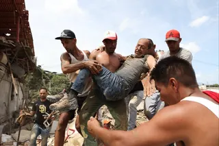 Neighbours carry a man rescued from the rubble of a collapsed building in La Guaira, Venezuela, on Thursday. Photo: AP