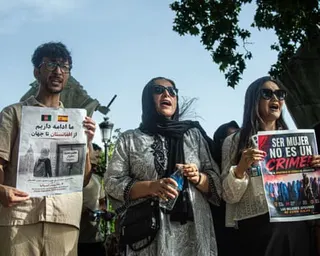 Three protesters hold signs in support of Afghan women at an outdoor demonstration