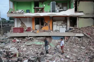 Two people stand outside a residential building missing its walls Catia La Mar.
