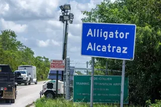 A sign reads 'Alligator Alcatraz' as cars pass by on a road