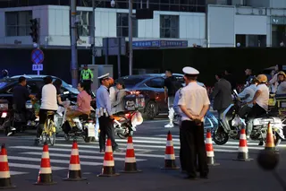 警察在靠近中信大厦的十字路口巡视，大厦外墙高层可见受损。