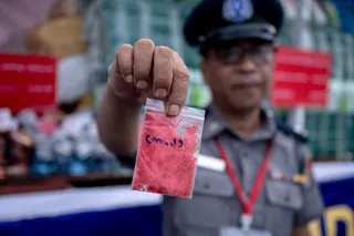 A Myanmar official shows a bag of ‘happy water’ drugs in Yangon on June 26, 2026. — AFP