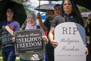 people hold signs that read 'rest in peace religious freedom'