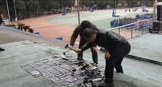 涉事學校老師拿鐵槌將沒收來的學生手機當眾砸毀。（視頻截圖）