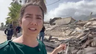 Vanessa Silva reporting from Venezuela showing destroyed buildings behind her