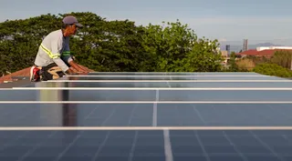 An installer with EcoSolutions places a solar panel onto the roof of a home in Manila on April 30. Photo: AP