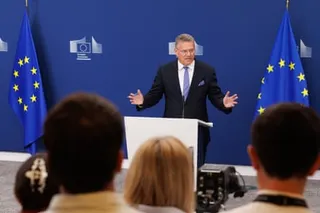 Maroš Šefčovič on a podium between two EU flags