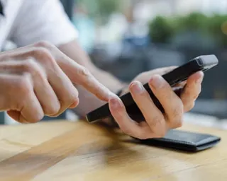 Close-up of unrecognizable man holding his smart phone while sitting at table in restaurant