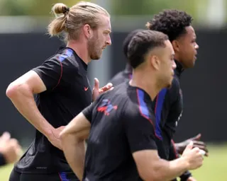 Tim Ream and teammates in black training kits jog together on a grass pitch during training