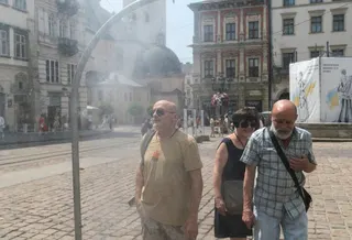 People cool themselves with water from a sprayer set up on a pavement in Lviv, Ukraine, on Monday. Some people in the nation were left without power after the latest Russian strikes, while others turned on air conditioners. Photo: EPA