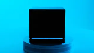 A Steam Machine in the dark, showing the blue LED light strip against the black chassis with a bright blue background