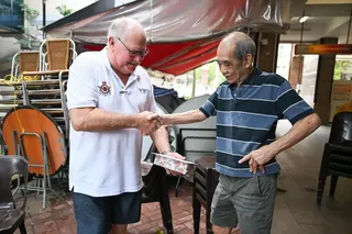 Retired pilot Ronald Haack (left) presenting an air force medallion to restaurant owner Au Kok Wing.