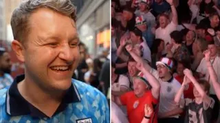 A man smiling with blonde hair dressed in a blue football jersey, with a crowd cheering to the right.