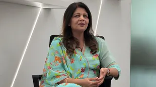 Shikha Goel is pictured inside the Cyber Security Bureau. She has long, dark hair and is wearing a bright green dress with flowers.