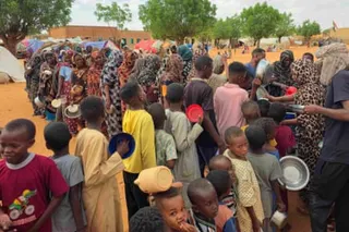 Dozens of women and children with bowls queue for food