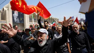 A man holds up his hands and wails in the crowd at the Grand Mosalla