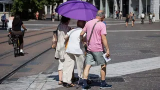 Elderly people with an umbrella used to protect themselves from the sun are walking through the streets of Grenoble. France, Isere, July 2, 2026. Illustrative image of the city of Grenoble during a heatwave.