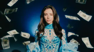 AI actress Tilly Norwood walks amidst falling money in a screenshot from its music video for Take the Lead