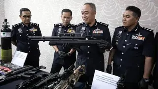 莫哈末阿尔威（左3）在警官的陪同，展示行动中起获的仿真步枪等。