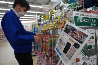 2025年10月24日，在岩手县花卷市一家商店，一名工作人员正在整理防熊喷雾广告旁的铃铛。（图取自法新社档案照）