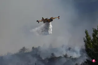 受持续热浪引发山火影响，法国政府投入地面和空中力量参与灭火。图为一架消防飞机星期一在靠近西班牙边界的法国西南部城市佩皮尼昂洒水扑灭野火。 （路透社）