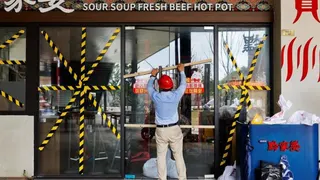 Qi Pengwen, regional manager of the Youth Coast shopping mall, secures the door of a restaurant with wooden bars