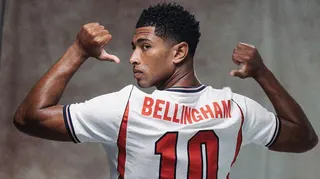 Jude Bellingham points to the number 10 on the back on his England shirt in a pre-World Cup publicity photograph