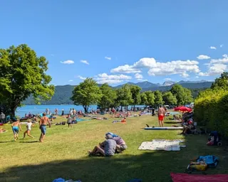 People playing and sitting on the grass by Lake Walchensee