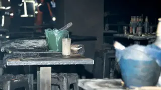 Tables and chairs are covered in ash at the scene of a fatal fire at a bar in Bangkok
