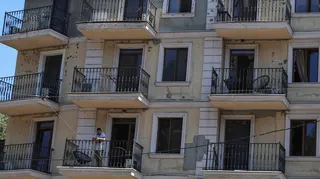A resident stands on a balcony of an apartment building damaged by a Russian missile strike, amid Russia's attack on Ukraine, in Odesa, Ukraine July 15, 2026.