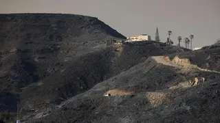 Burnt hills and a single house in the distance after wildfires through Almeria province, Spain.