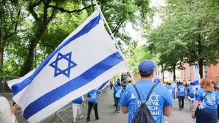 A marcher carries an Israeli flag while walking up Fifth Avenue in New York.