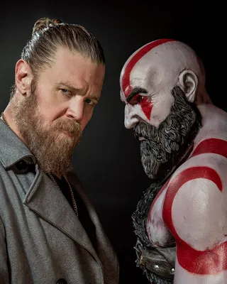 Actor Ryan Hurst standing next to a statue of Kratos from God of War