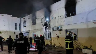 Rescuers and police officers work at the site of a fire at an orphanage near Algiers on 16 July.